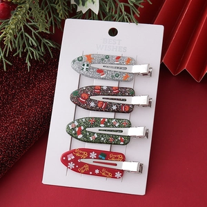 Close-up of four festive Christmas hair clips with Santa and reindeer motifs on a white card