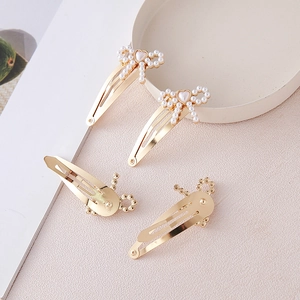 Detailed set of four gold metal hair clips with white pearl bow and heart accents