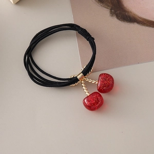 Gros plan sur élastique cheveux cerise rouge scintillante avec détails dorés chic