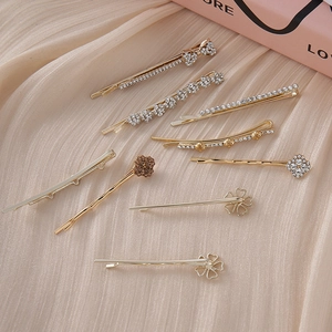 Set of 8 gold rhinestone hair clips featuring bow and clover designs on beige fabric