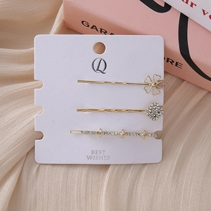 Detailed view of 3-piece gold floral rhinestone hair clip set on a white display card