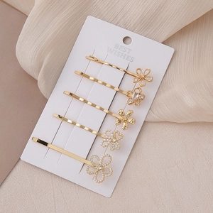 Golden flower hair clip set with pearls and rhinestones on elegant cream fabric