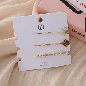 Close-up of golden clover hair clips set with brown rhinestones on a satin background