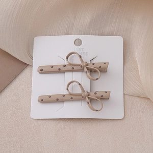 Polka dot bow hair clips set on display card with soft beige mesh background