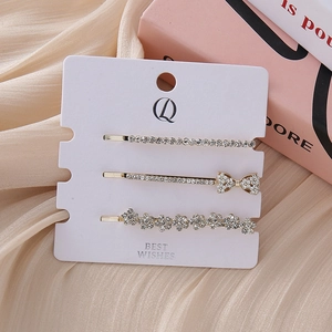 Detailed macro view of three rhinestone hair clips with floral and bow designs on card