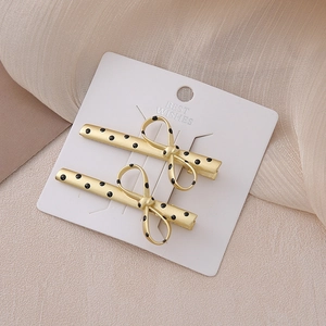 Elegant gold metal hair clips with black polka dot bows on white display card