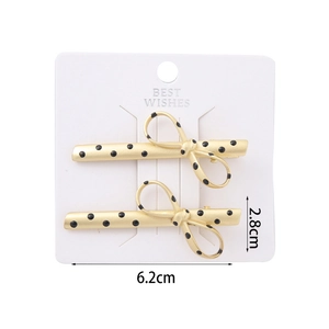 Set of two elegant matte gold hair clips with black polka dots on white card