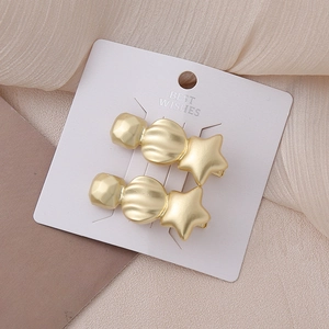 Detail of matte gold star hair clips with geometric beads on an elegant card