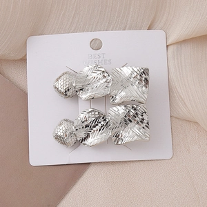 Detail showing two silver geometric hair clips with textured finish on white card base