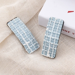 Detailed close-up of light blue houndstooth tweed fabric hair clips in a set of two