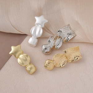 Detail of four geometric hair clips with star and matte finish on silk fabric
