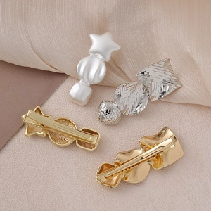 Detail of star-shaped and geometric hair clips with pearlescent and silver metallic textures