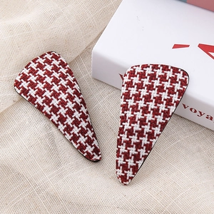Macro view of red and white houndstooth fabric hair clips on a textured background