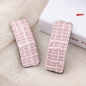 Close-up of pink houndstooth tweed hair clips with detailed woven texture and elegant style