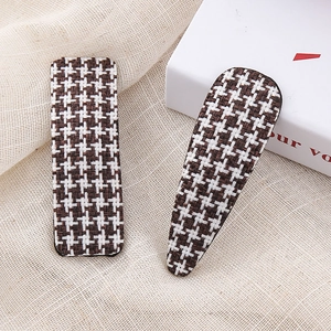 Close-up of brown houndstooth pattern fabric hair clips set on a beige fabric background