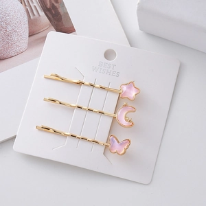Set di tre fermagli per capelli dorati con stella luna e farfalla su cartoncino