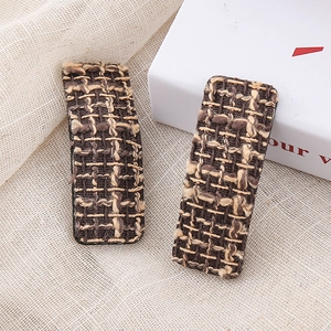 Close-up detail of vintage houndstooth pattern tweed hair clips on rustic linen fabric