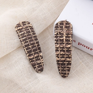 Close-up of retro houndstooth tweed BB hair clips in brown and beige on fabric