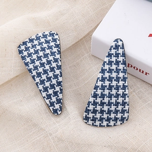 Detailed view of blue and white houndstooth triangular hair clips on textured linen