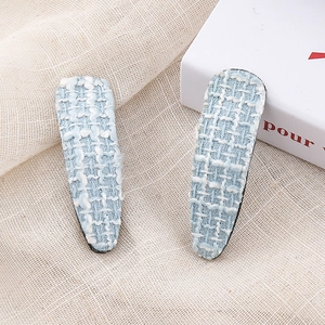 Detailed macro of light blue houndstooth tweed BB hair clips with woven texture