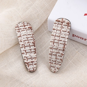 Detail view of water drop-shaped houndstooth tweed hair clips with woven texture