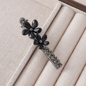 Detailed macro view of silver floral hair clip with black gems and sparkling crystals