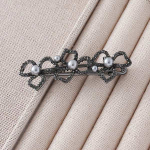 Macro view of gunmetal flower hair clip featuring grey pearls and sparkling rhinestones