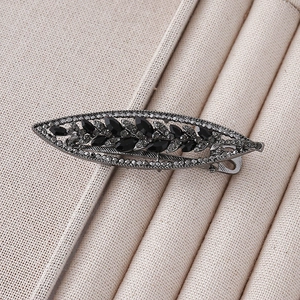 Macro shot of vintage leaf-shaped hair clip with black gems and grey rhinestones