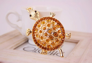 Détail macro d'un pendentif tortue en métal doré serti de strass couleur ambre