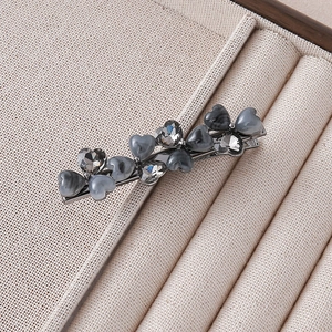 Detail view of heart-shaped grey stones and crystals on a silver hair clip base