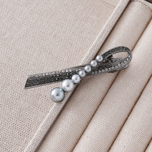 Detail of vintage gray pearl hair clip with rhinestones on beige jewelry display case