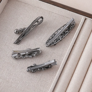Detailed back view of four gunmetal hair clips with duckbill and snap closure on tray