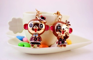Detail of adorable monkey couple keychains with colorful enamel on a coffee cup