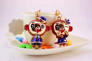 Detail of cute enamel monkey couple keychains in gold finish on a white ceramic tray