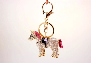 Close-up of sparkling rhinestone horse keychain with pink enamel details on golden metal