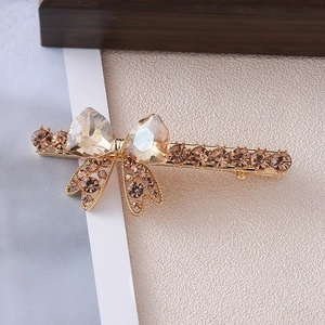 Detail of a champagne crystal heart bow hair clip with brown rhinestones and gold base