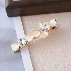 Detailed macro view of heart-shaped opal petals and crystal rhinestones on a gold hair clip