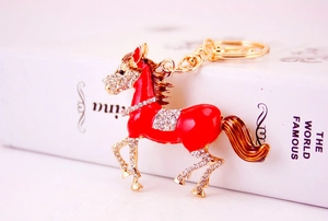 Detail of red enamel horse keychain with sparkling rhinestones and golden hardware