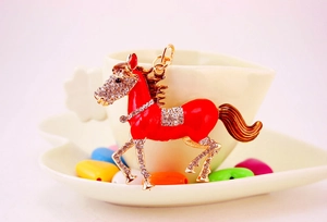 Detailed close-up of a red enamel horse keychain with gold metal and sparkling crystals