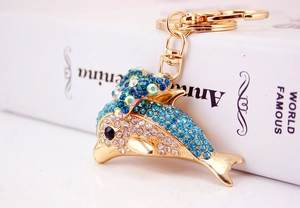 Macro view showing blue crystal rhinestones on a golden dolphin keychain accessory