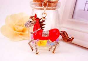 Close-up of red enamel horse keychain with sparkling crystals and gold metal hardware