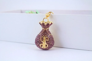 Close-up of golden money bag keychain with purple rhinestones and dollar sign