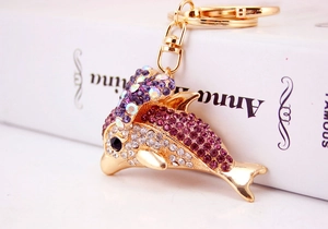 Detailed close-up of a golden dolphin keychain with purple and pink crystal rhinestones
