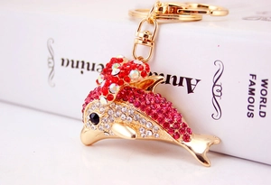 Macro detail of dolphin keychain encrusted with red and pink rhinestones on gold metal