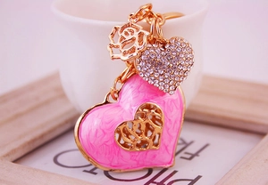 Macro detail of pink enamel heart keychain with rhinestones and hollow rose pendant