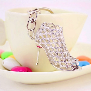 Elegant silver high heel shoe keychain with intricate hollow mesh design on a white cup