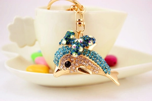 Close-up of dolphin keychain with colorful rhinestones on a ceramic cup rim