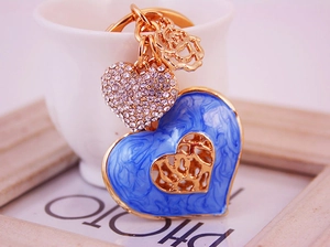 Close-up of blue heart keychain with sparkling rhinestones and enamel rose pendant
