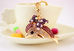 Detailed close-up of a golden dolphin keychain with purple rhinestones and a cute bow
