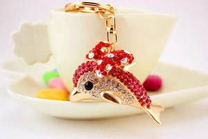 Sparkling crystal dolphin keychain with red and white rhinestones on a coffee cup
